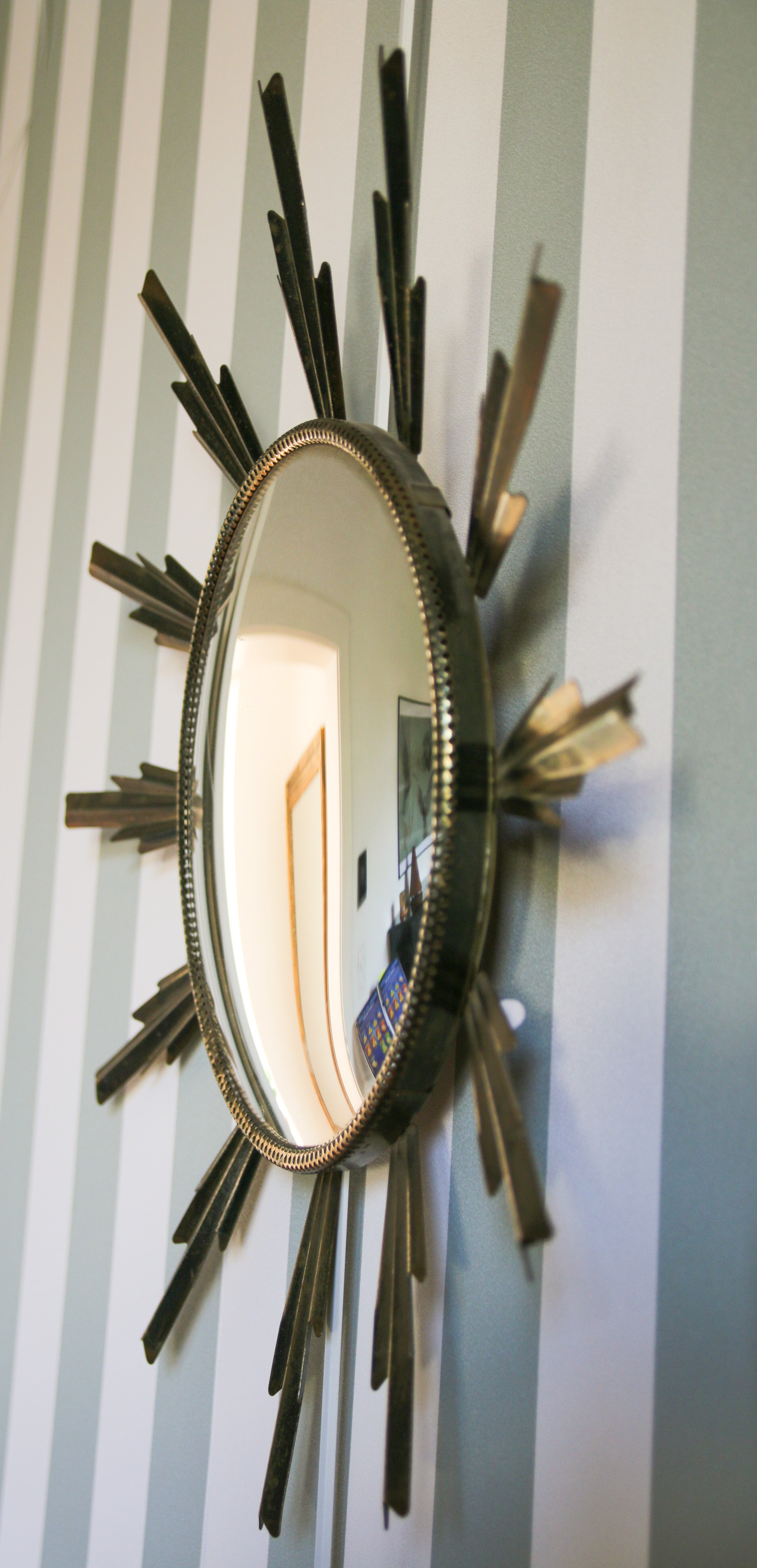 Vue de profil d'un miroir de sorcière convexe, rayons soleil en métal doré, détail du relief et de la courbure du verre, Studio Cinquante.