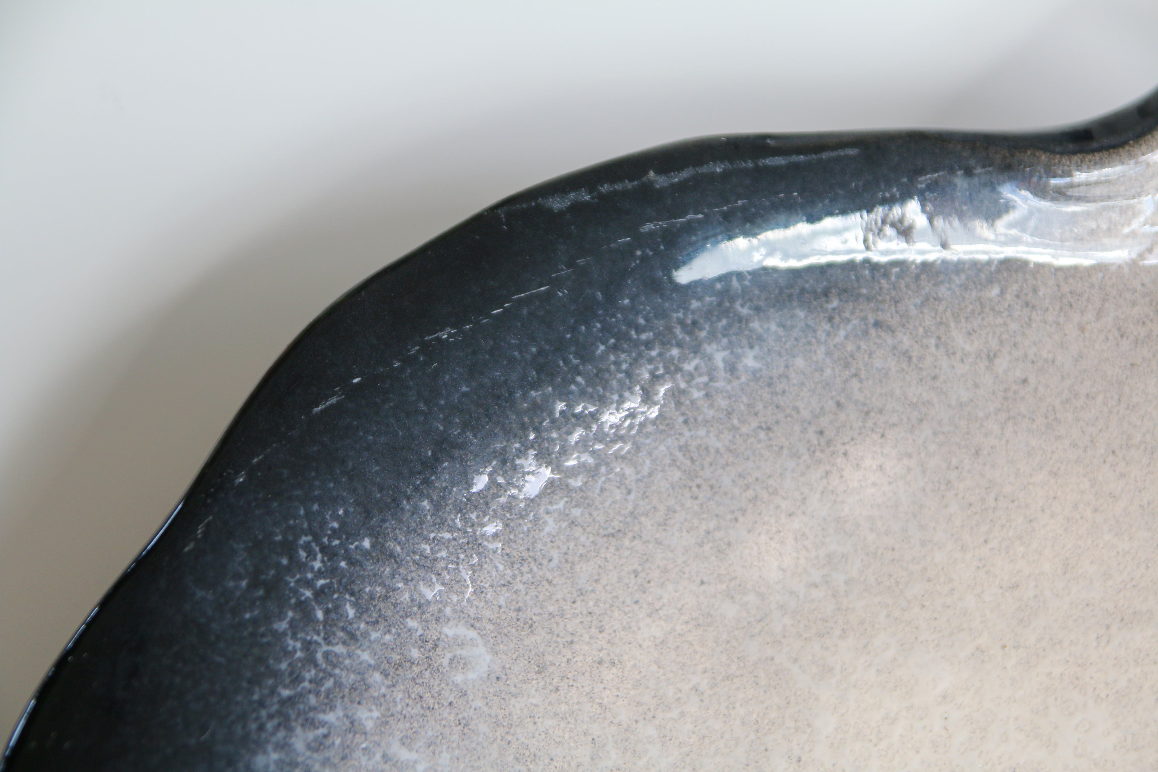 Détail de l'émaillage bicolore noir et blanc sur céramique de Pol Chambost, finition brillante