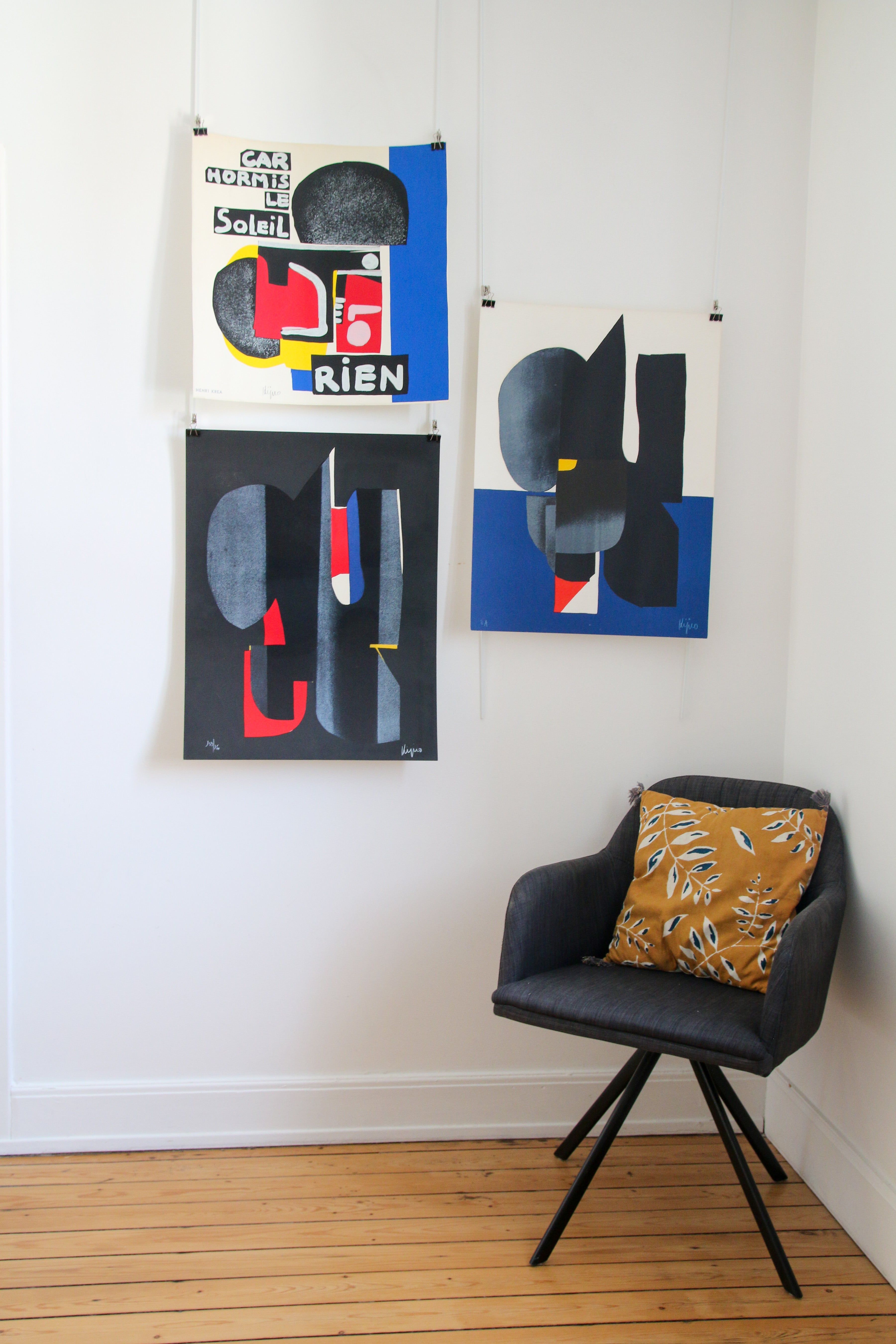 Mise en situation de la sérigraphie Ladislas Kijno "Car hormis le soleil rien" dans un salon moderne avec fauteuil anthracite et coussin ocre.