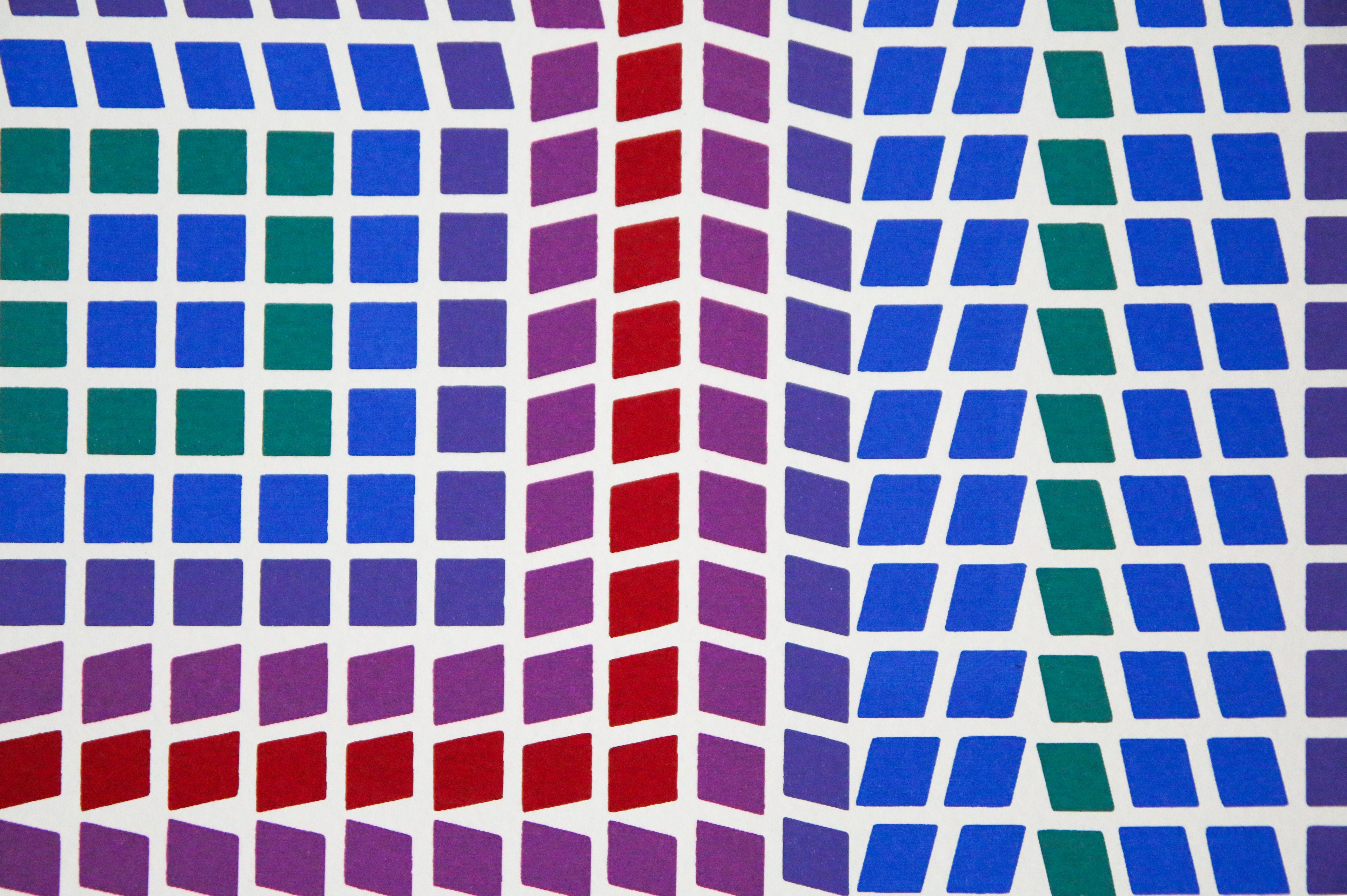 Détail géométrique et contraste de couleurs bleu et rouge, vert et violet d'une sérigraphie cinétique de Vasarely.